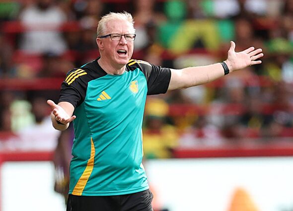 Un individu, vêtu d'un uniforme de sport vert et noir avec des accents jaunes, fait des gestes actifs avec les deux bras tendus. 