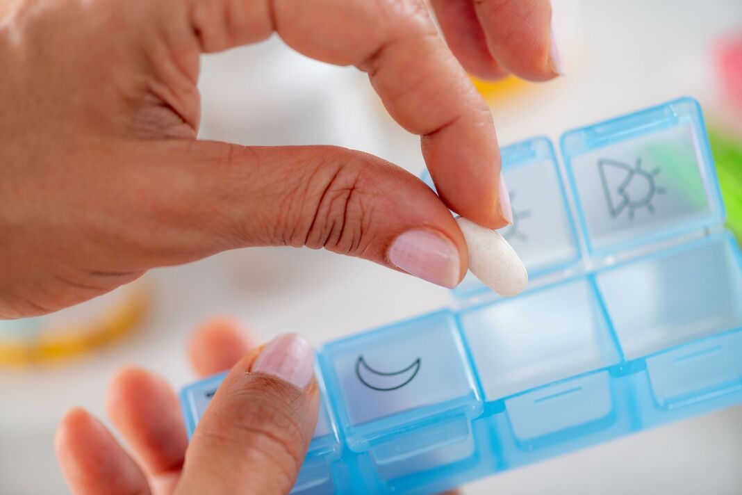 Femme préparant un programme de pilules organisé en organisant les médicaments dans un pilulier. Capture la discipline de planification, un étiquetage clair et une intégration fiable Femme préparant un programme de pilules organisé en organisant les médicaments dans un pilulier. Capture la discipline de planification, un étiquetage clair et une intégration fiable