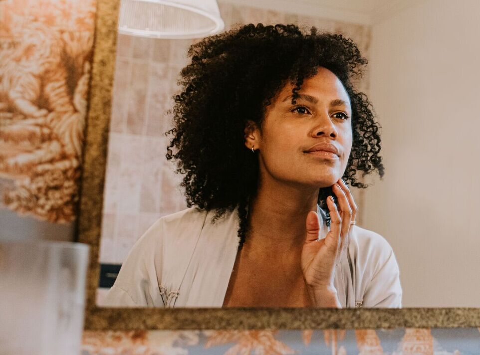 Une belle femme examine sa peau dans un miroir de salle de bains Une belle femme examine sa peau dans un miroir de salle de bains