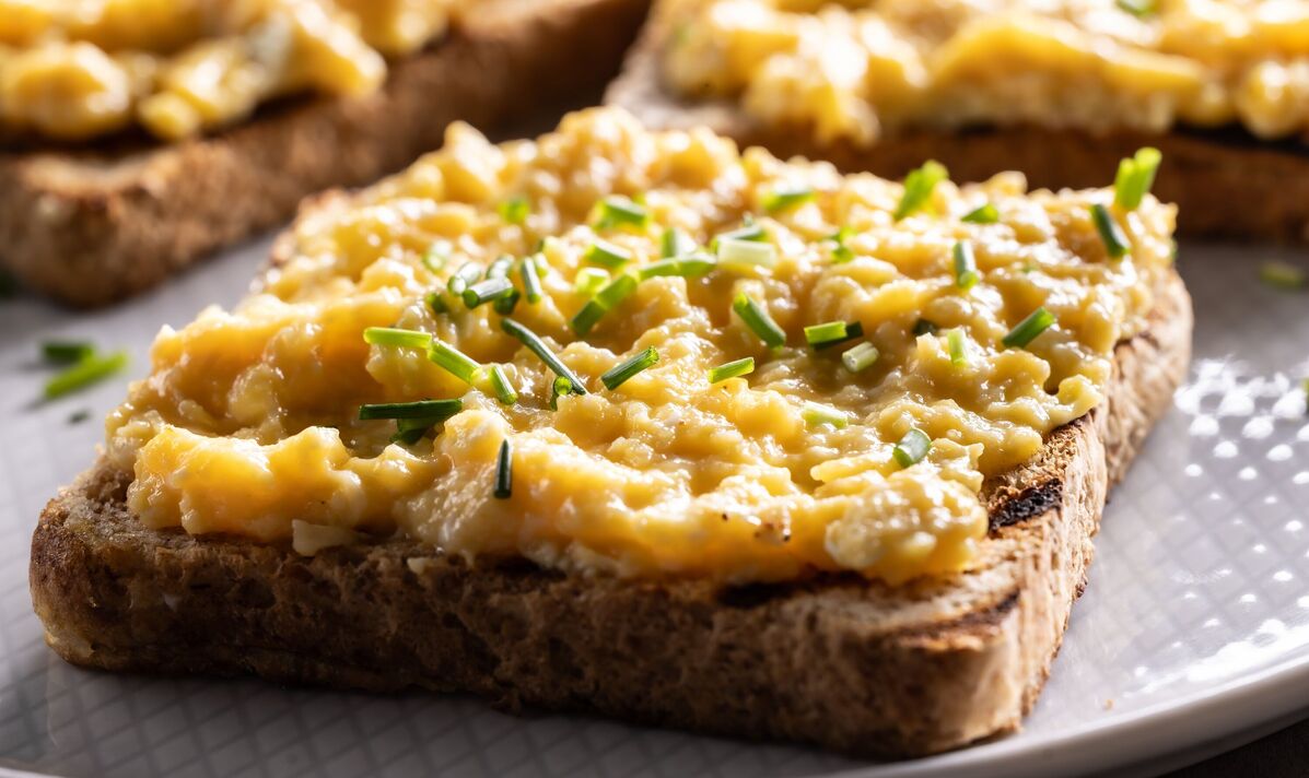 Pains de mie grillés avec œufs brouillés et ciboulette sur une assiette comme petit-déjeuner sain