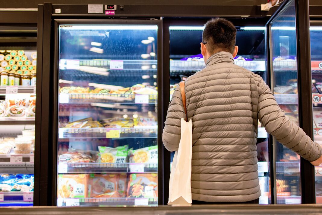 Homme ouvrant un congélateur dans un supermarché Homme ouvrant un congélateur dans un supermarché